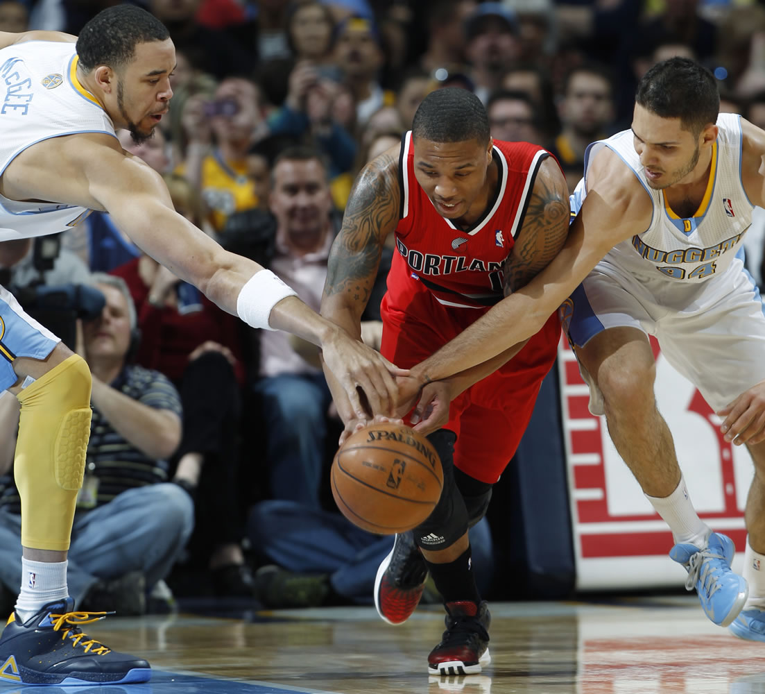 Portland Trail Blazers guard Damian Lillard, center, battles for control of a loose ball with Denver Nuggets forward JaVale McGee, left, and guard Evan Fournier.
