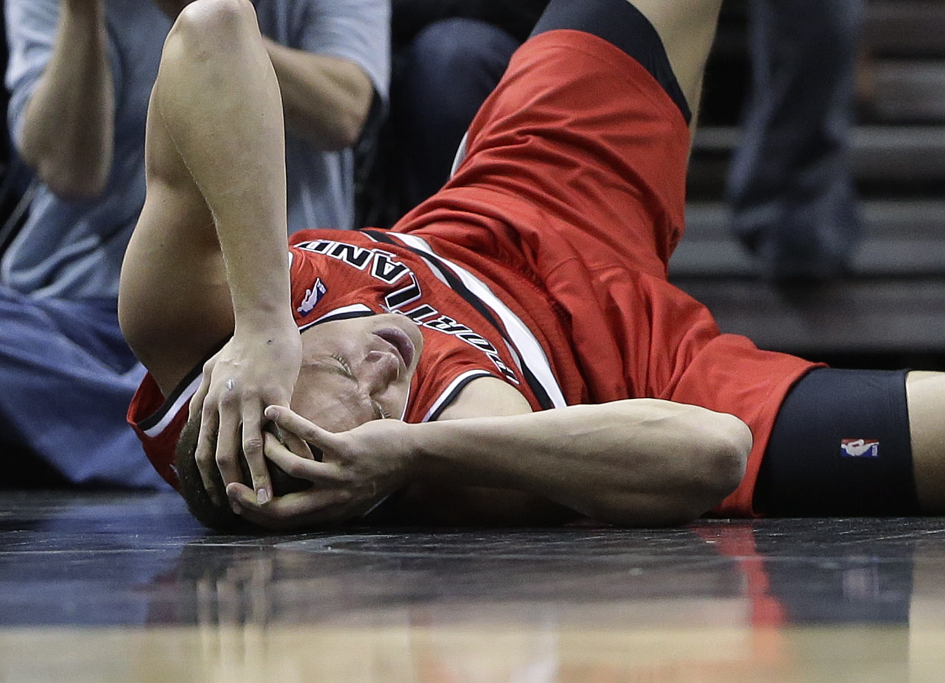 Portland Trail Blazers' Meyers Leonard holds his head after he was injured during the first half of an NBA basketball game against the San Antonio Spurs, Friday, March 8, 2013, in San Antonio.