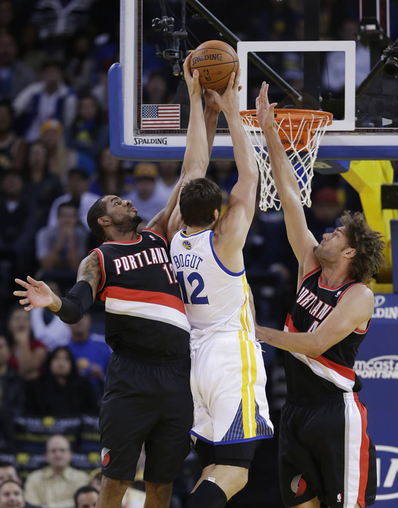 Portland Trail Blazers' LaMarcus Aldridge, left, blocks a shot attempt from Golden State Warriors' Andrew Bogut (12) during the first half of an NBA preseason basketball game on Thursday, Oct. 24, 2013, in Oakland, Calif.