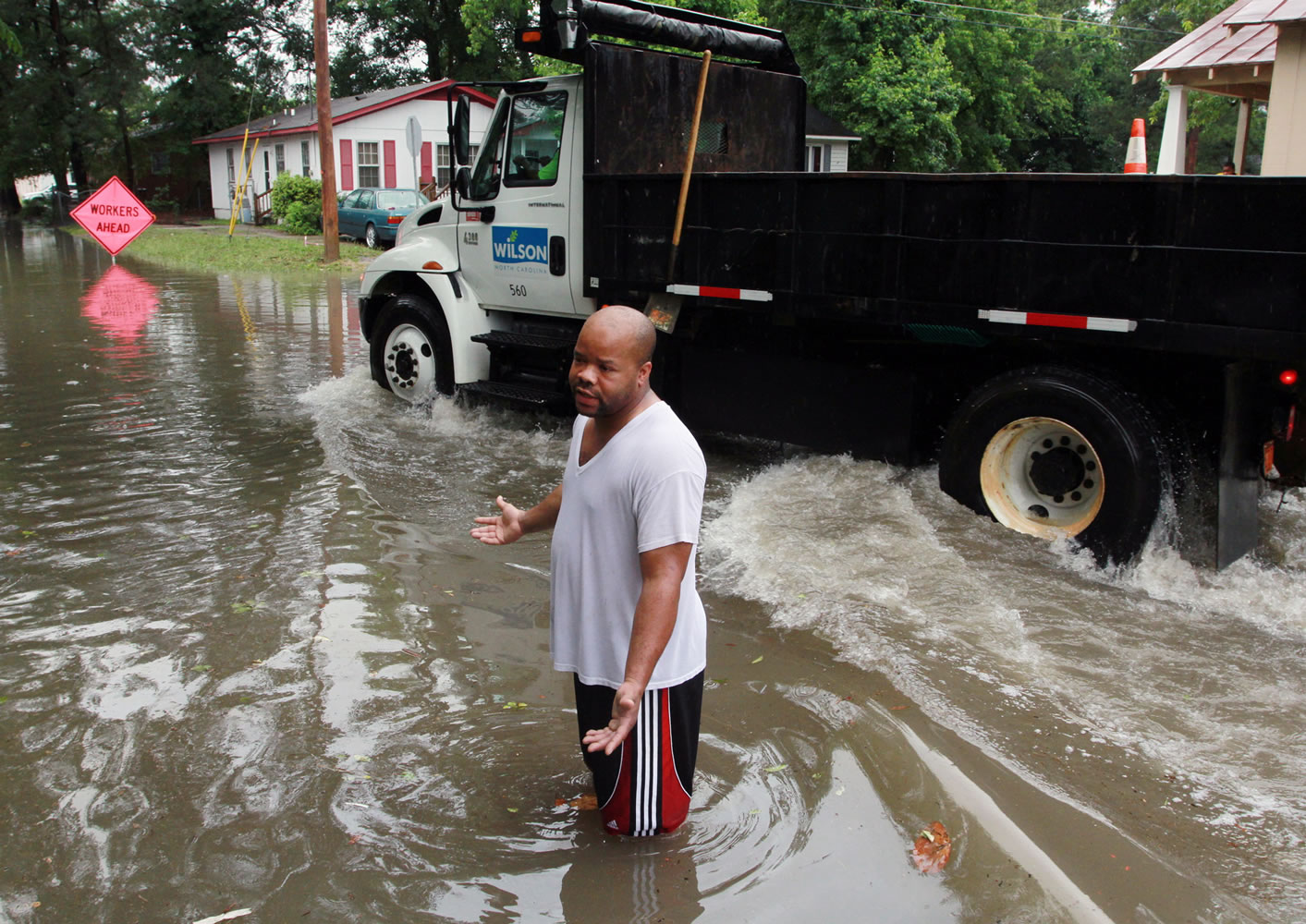 Ernest Lucas III attempts to walk through flooded sections of Singletary and Elvie streets as a city of Wilson truck drives through the area, Friday in Wilson, N.C.