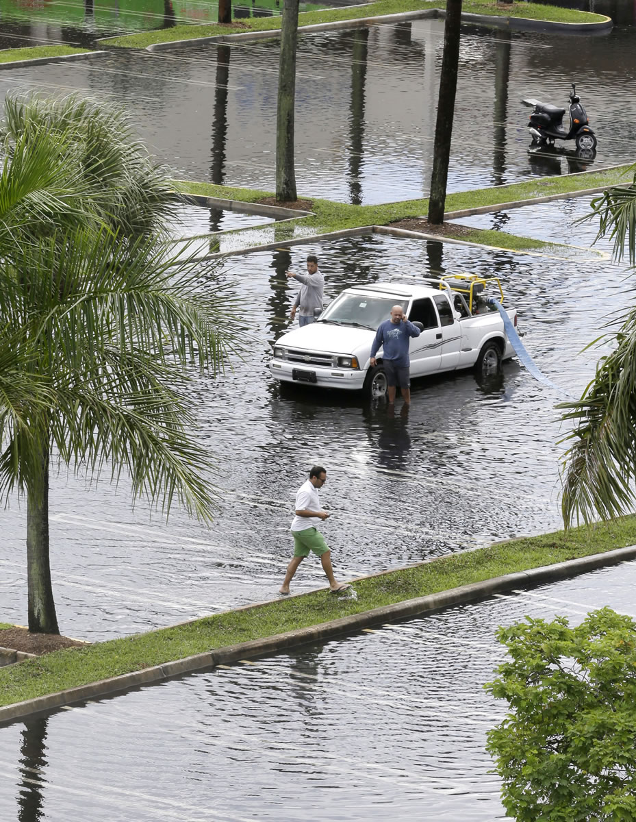 Workers pump water from the parking lot of the Dadeland Plaza shopping center Thursday after heavy rains in Pinecrest, Fla., a suburb of Miami.