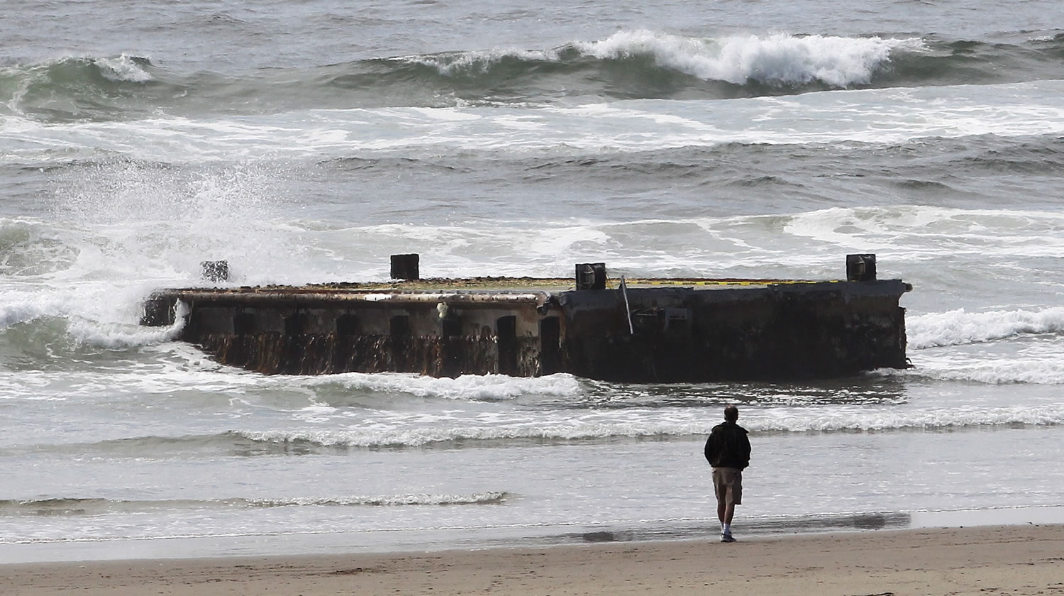 Associated Press files
A man looks at the tsunami dock that washed ashore on Agate Beach in Newport, Ore., in June. Another dock has washed ashore in Washington.
