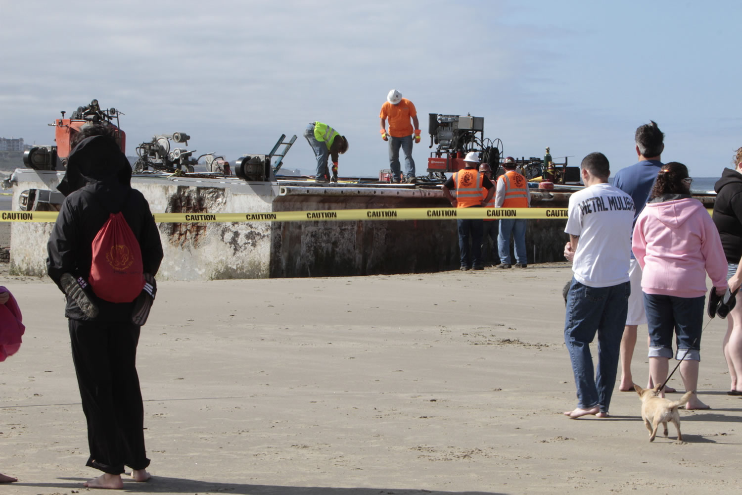Workers use a cable-cutting system Wednesday to section the giant Japanese dock that was torn away by last year's tsunami and washed ashore in Newport, Ore.