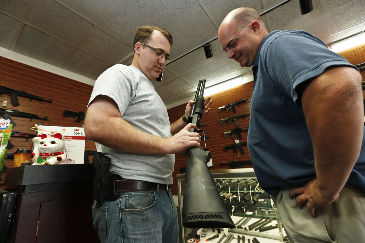 Black Weapons Armory store owner Tommy Rompel, left, shows former mayoral candidate Shaun McClusky a shotgun at the Tucson, Ariz., store on Thursday.