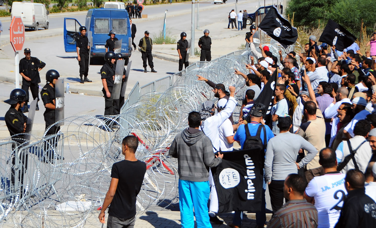 Protestors, right, face-off against riot police officers guarding the U.S. Embassy in Tunis on Friday, Sept. 14.