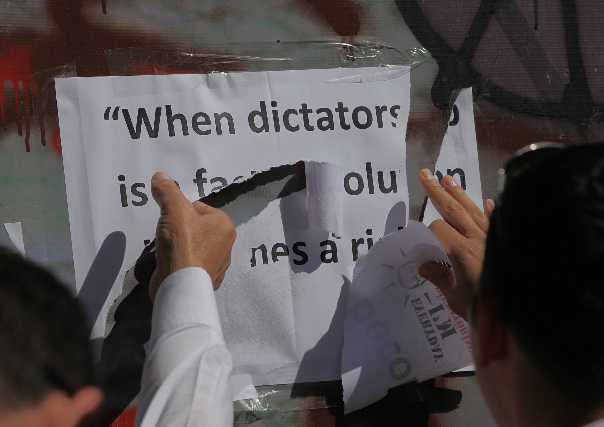 Plainclothes police officers remove the words of French writer Victor Hugo -- &quot; when dictatorship is a fact, revolution becomes a right&quot; -- placed on a monument by Turkish protesters, who were sitting in Kugulu Park in Ankara, Turkey, on Thursday.