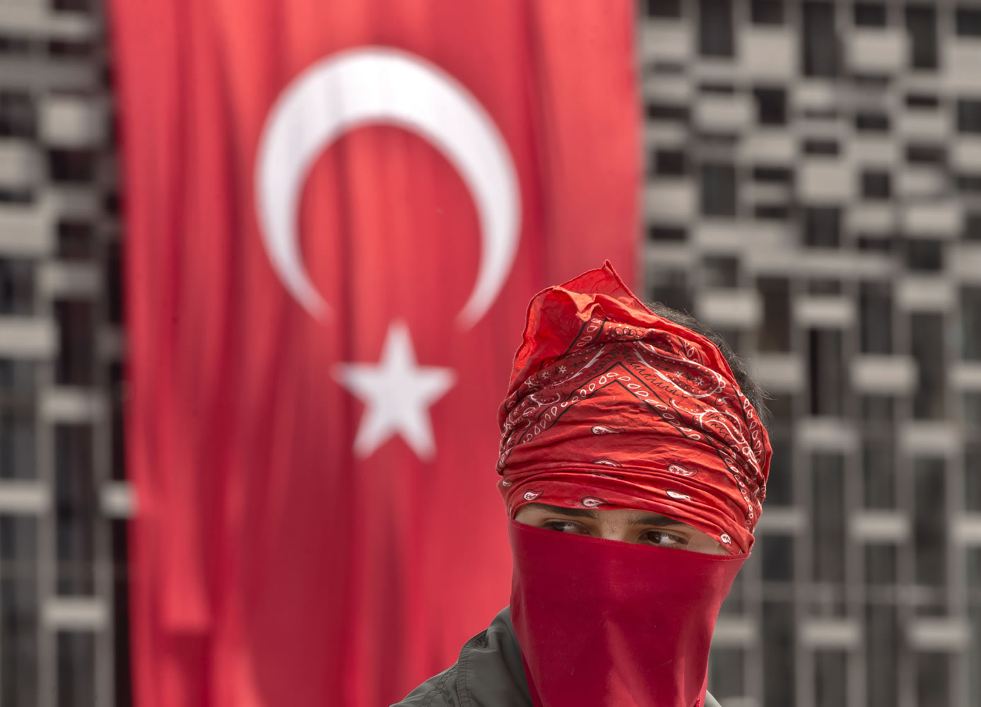 A masked protester is backdropped by a Turkish flag on the edge of Gezi Park, in Istanbul, Turkey.
