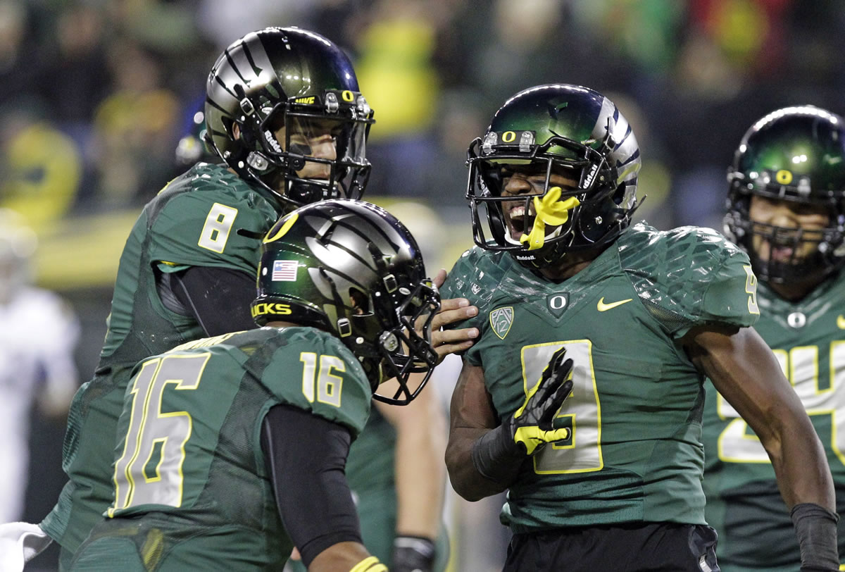 Oregon running back Byron Marshall, right, celebrates his touchdown with teammates Daryle Hawkins (16) and quarterback Marcus Mariota (8) during the second half of an NCAA college football game against UCLA in Eugene, Ore., Saturday, Oct. 26, 2013. Marshall ran for 133 yards and three touchdowns for a 42-14 victory.