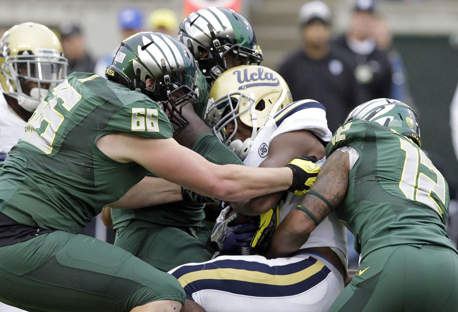 UCLA running back Paul Perkins, middle, is wrapped up by Oregon defenders Taylor Hart, left, and Brian Jackson during the first half of an NCAA college football game in Eugene, Ore., Saturday, Oct. 26, 2013.