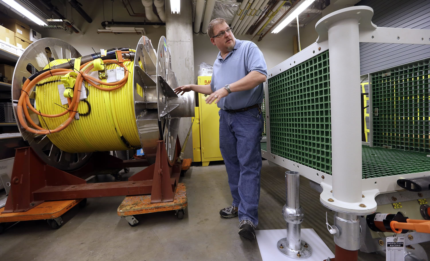 Senior field engineer Larry Nielson talks about the 1,000 meter-long cable, left, that will be tethered to the frame at right as part of an underwater observatory being built at the Applied Physics Lab at the University of Washington in Seattle.