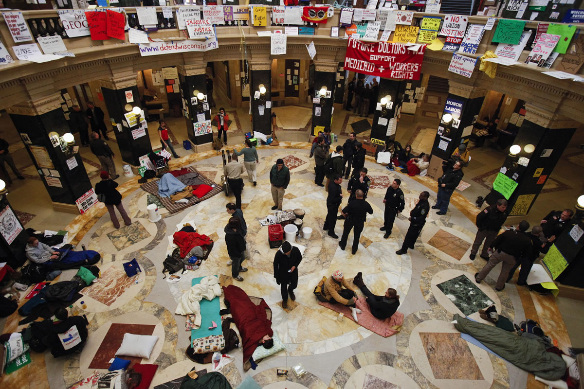 This Feb. 28, 2011 file photo shows protests continuing at the state Capitol in Madison, Wis., as police and demonstrators gather on the rotunda floor where opponents to the governor's bill to eliminate collective bargaining rights for many state workers had been sleeping.