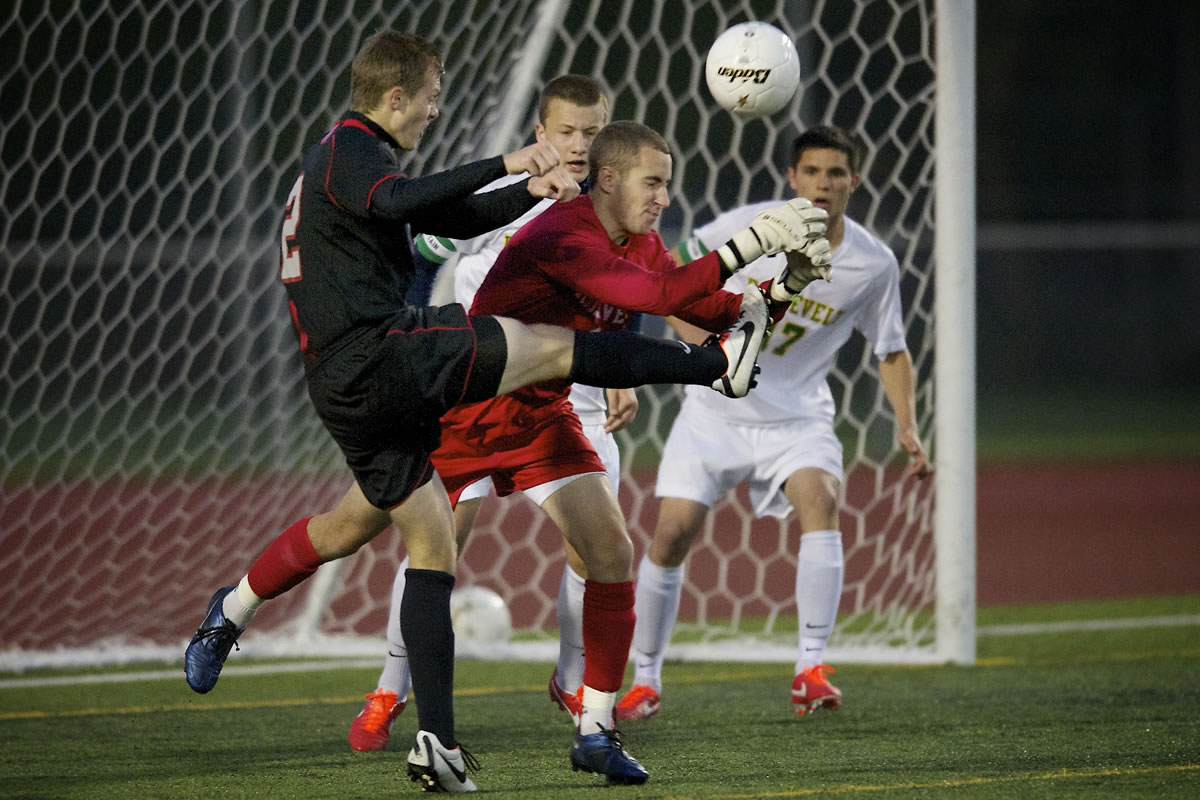 Union's Tyler Shadix, left, strikes the ball away from Roosevelt goalkeeper Julien Leveque on a free kick by Union's Mitch Wheelon for the first goal of the Titans' 2-1 Class 3A state semifinal victory Friday night in Puyallup.