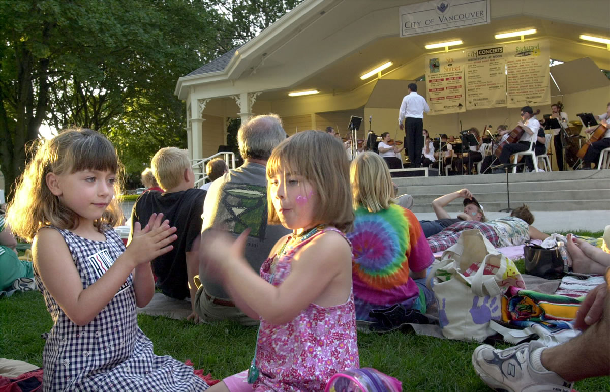 Gabrielle Gache, 5 and Olivia Kerr, 3, clap with the beat of the music from the Vancouver Symphony in Esther Short Park.