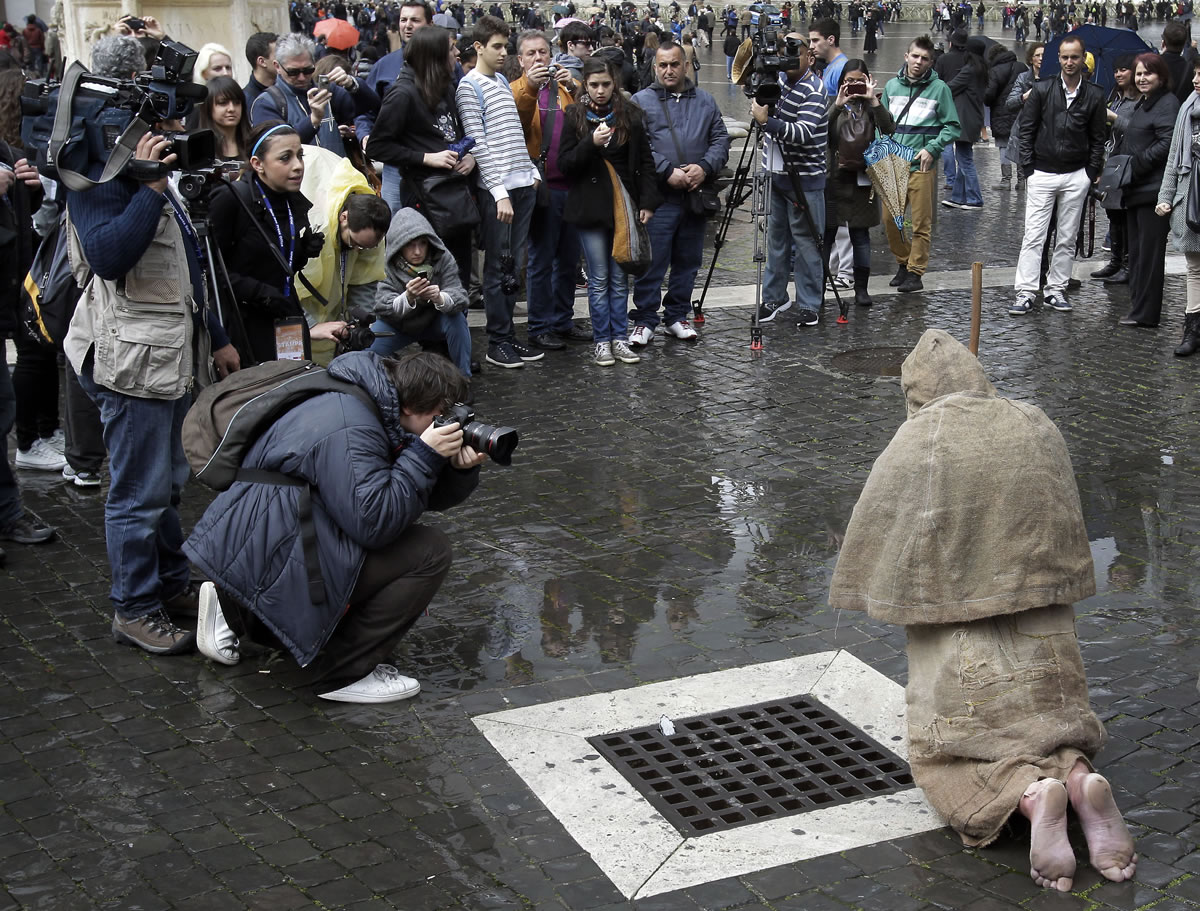 Members of the media take photos of a pilgrim in St. Peter's Square during a mass at St.