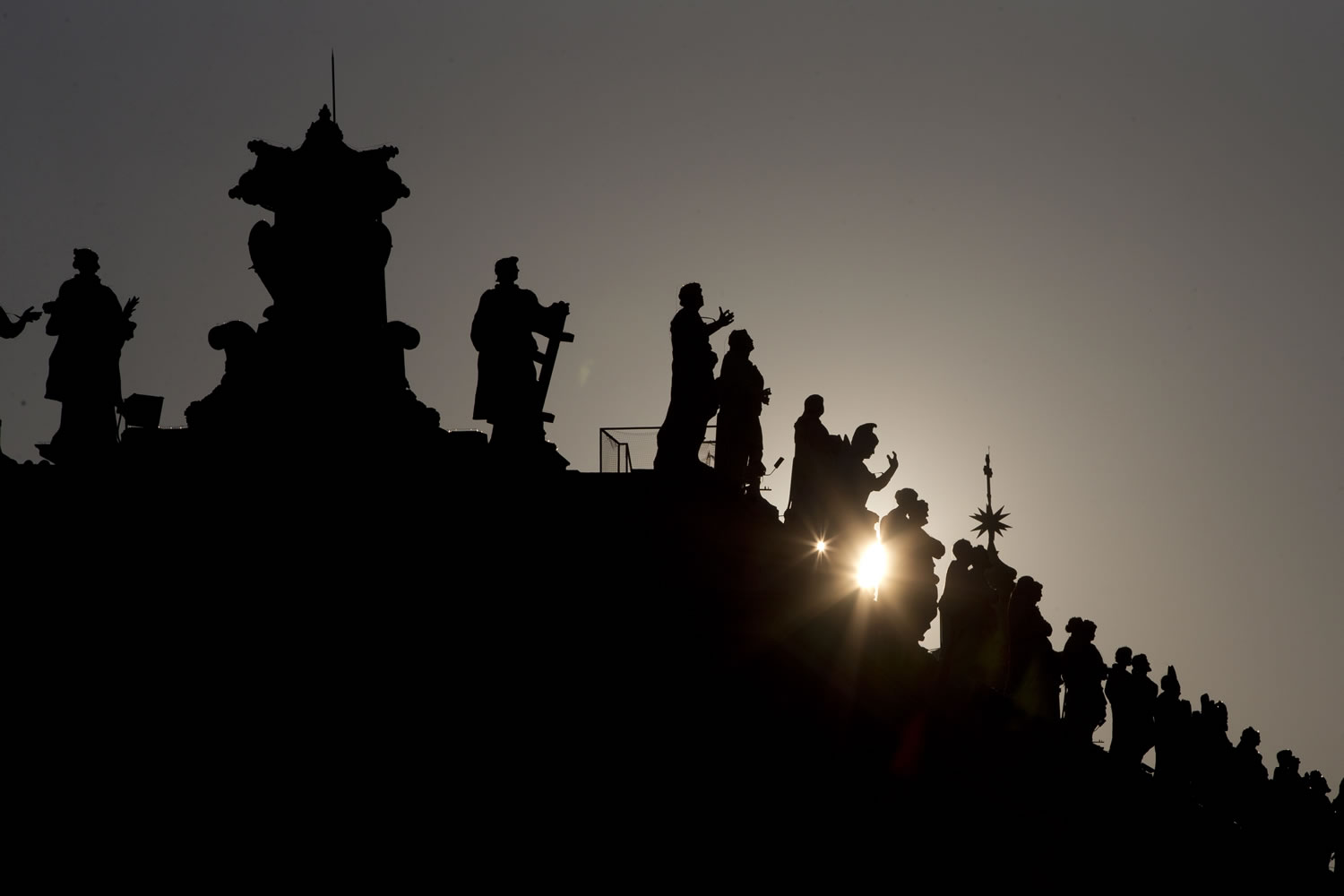 The sun sets behind the statues on top of the Bernini colonnade in St.