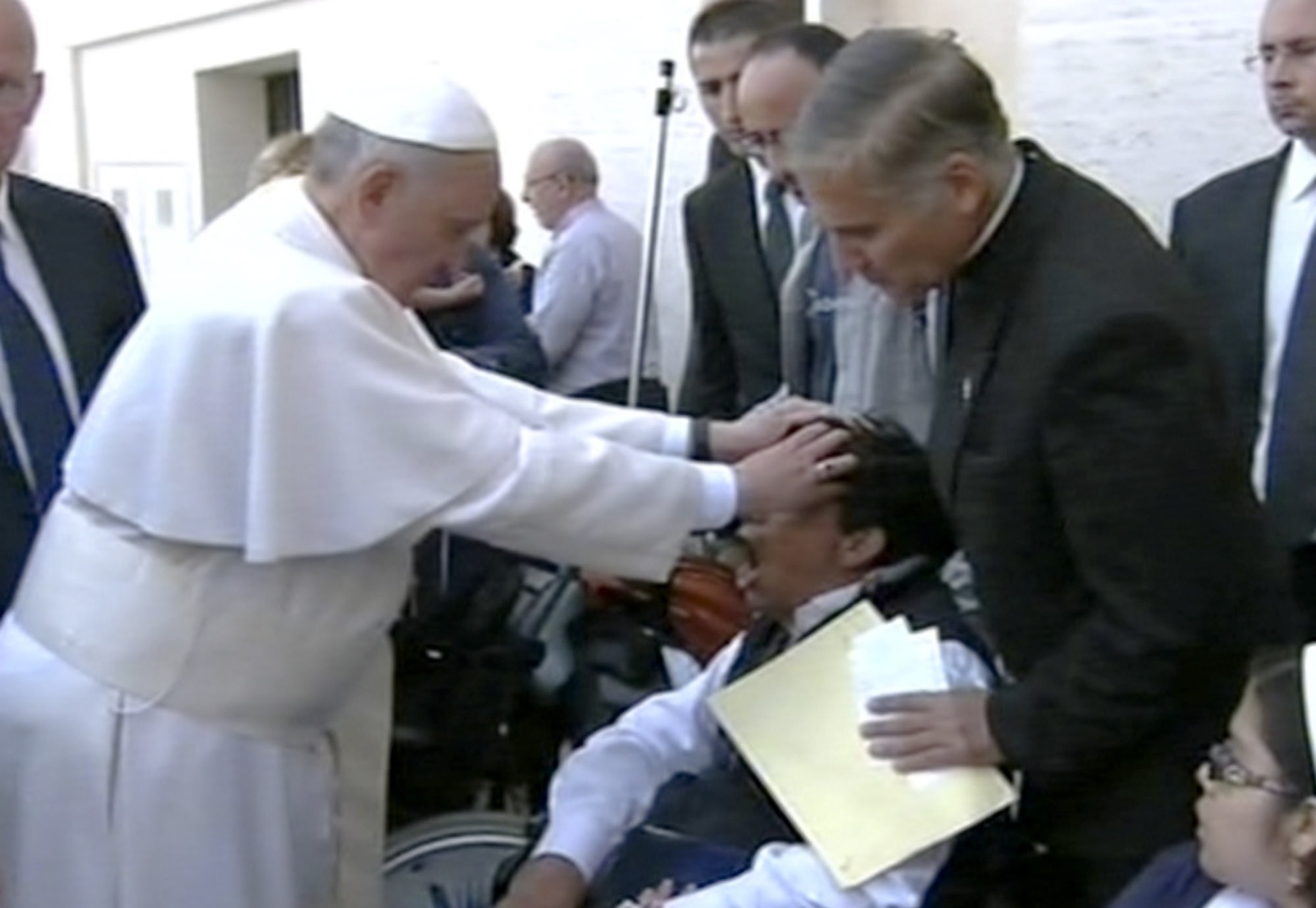 Pope Francis lays his hands on the head of a young man on Sunday after celebrating Mass in St. Peteris Square. The young man heaved deeply a half-dozen times, convulsed and shook, and then slumped in his wheelchair as Francis prayed over him.
