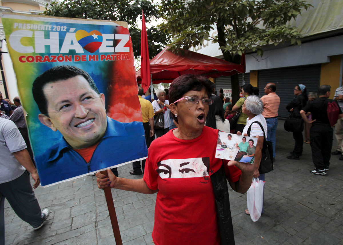 A supporter of Venezuela's President Hugo Chavez holds photos of Chavez in Bolivar square in Caracas, Venezuela on Tuesday. Venezuela's Vice President Nicolas Maduro announced on Tuesday that Chavez has died.