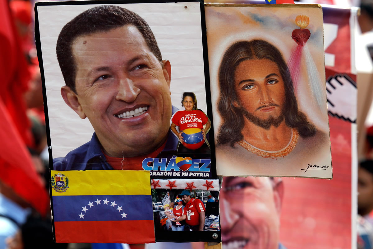 A photograph of Venezuela's President Hugo Chavez, left, flanks one of Jesus Christ, held by a Chavez supporter at a rally Wednesday in Caracas, Venezuela.