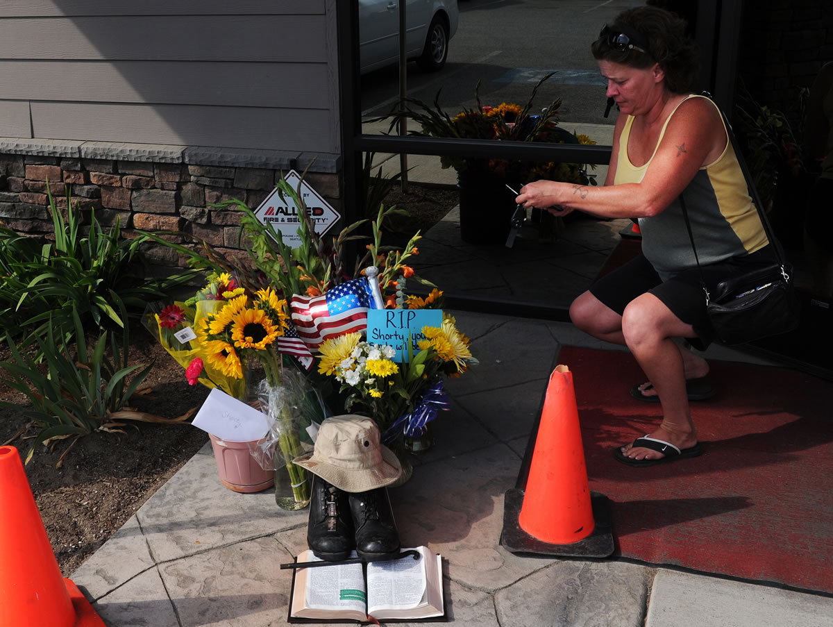 In this Aug. 22, 2013, photo, Lill Duncan takes a photo of a memorial for Delbert Belton, an 88-year-old World War II veteran who was beaten to death, in Spokane, Wash. Police have arrested one of two teens suspected of fatally beating Belton, who had survived the battle for Okinawa, and the police chief said Friday, Aug. 23, that the brutal attack does not appear to have been racially motivated.