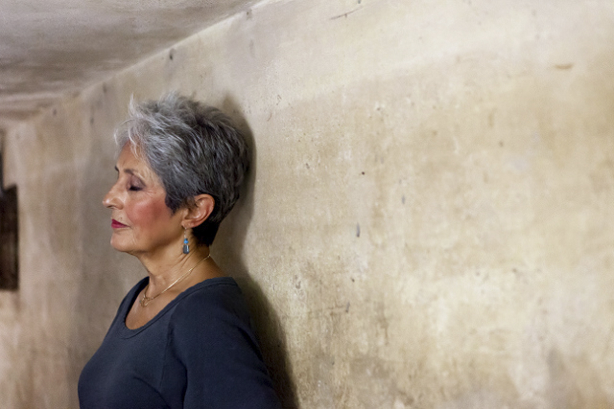 Joan Baez stands with her back to the wall of an historic bomb shelter under the Metropole Hotel in Hanoi, Vietnam.