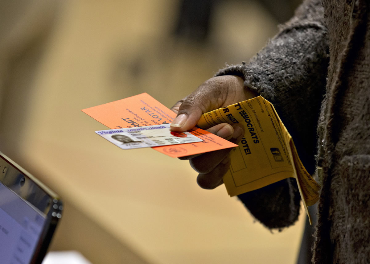 A voter holds their voting permit and ID card at the Washington Mill Elementary School near Mount Vernon, Va.