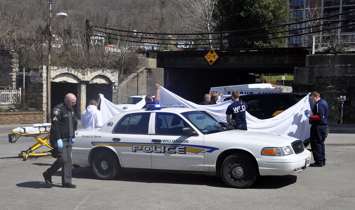 Law enforcement officers and emergency service personnel cover the vehicle at the scene of the shooting in downtown Williamson, W.Va., on Wednesday, where Sheriff Eugene Crum was shot and killed at point blank range.