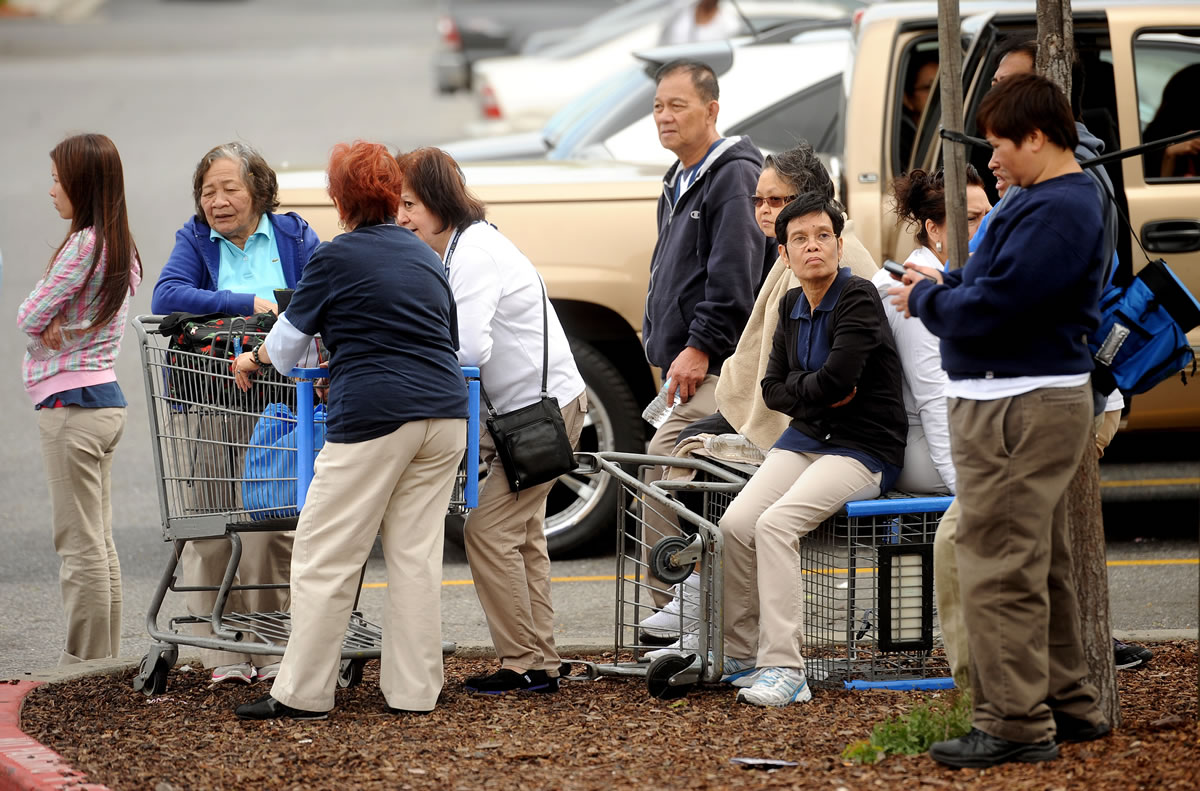 Walmart workers gather outside a Walmart in San Jose, Calif., after a motorist drove through a store entrance and began assaulting shoppers on Sunday.
