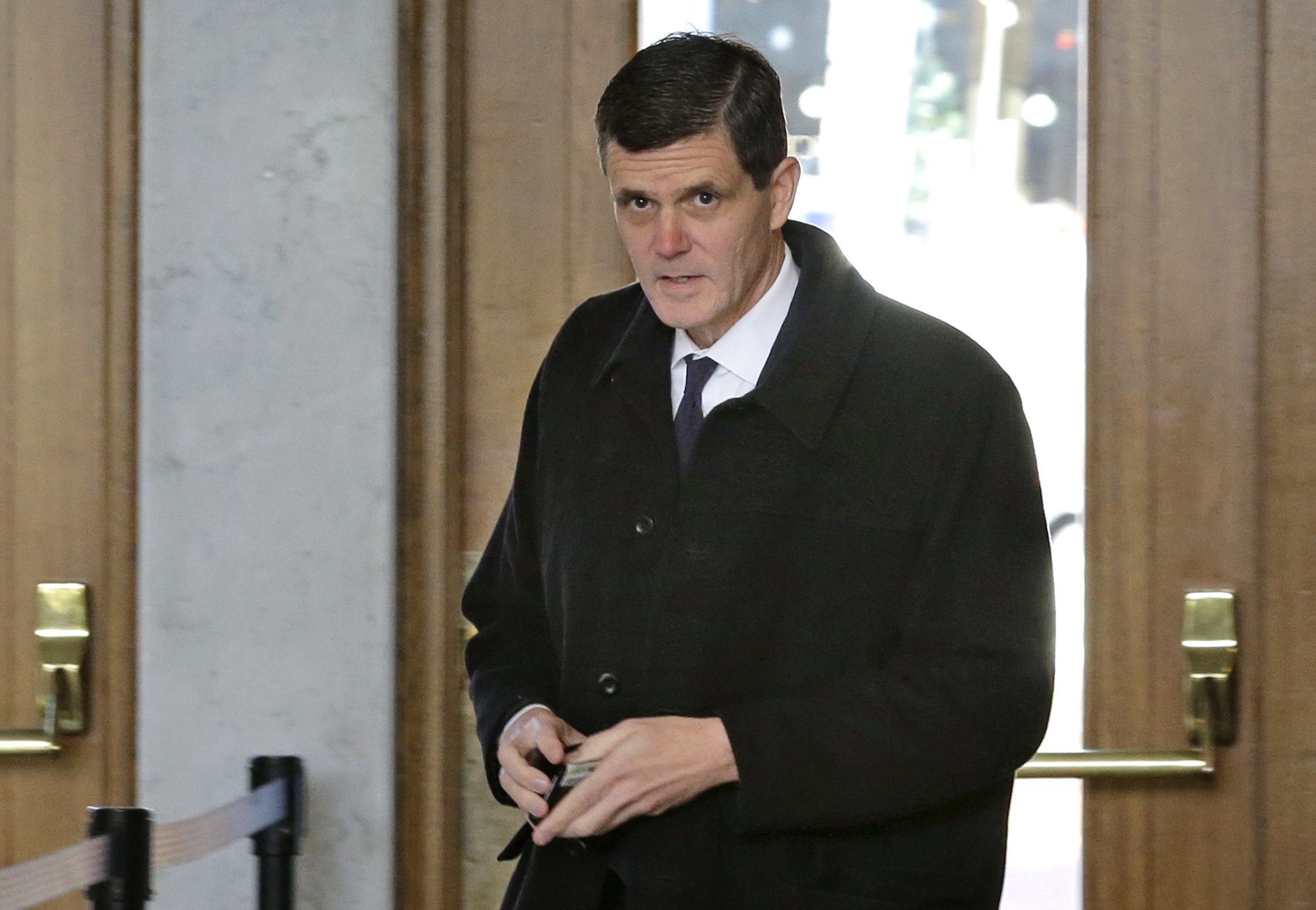 Washington Auditor Troy Kelley holds his wallet after showing his identification as he arrives for a federal court hearing Tuesday in Tacoma. Kelley was asking a judge to force the Justice Department to return $908,000 that was seized from Kelley after he was charged criminally with possession of more than $1 million in stolen money as well as money laundering. (AP Photo/Ted S.