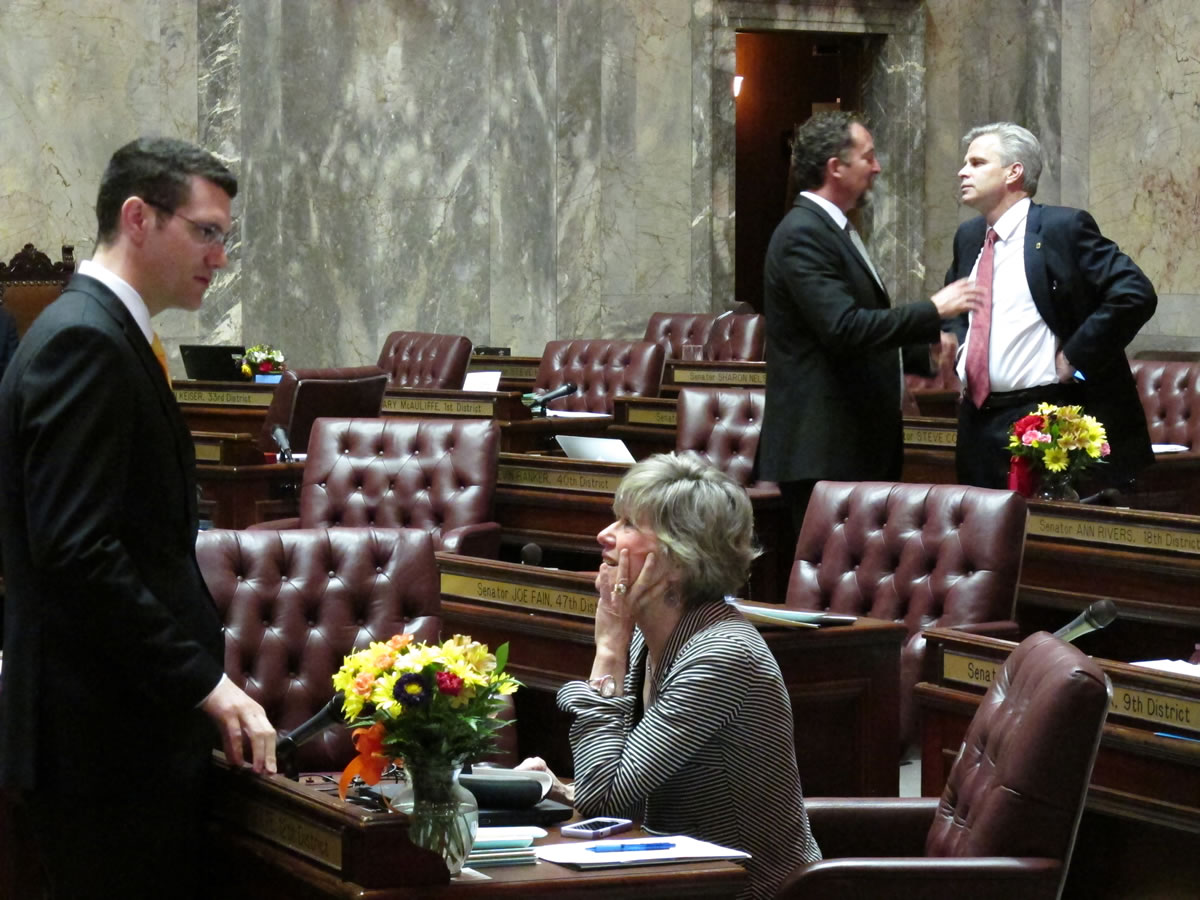 Washington state lawmakers mill about on the Senate floor on the last day of the regular legislative session on Sunday in Olympia.