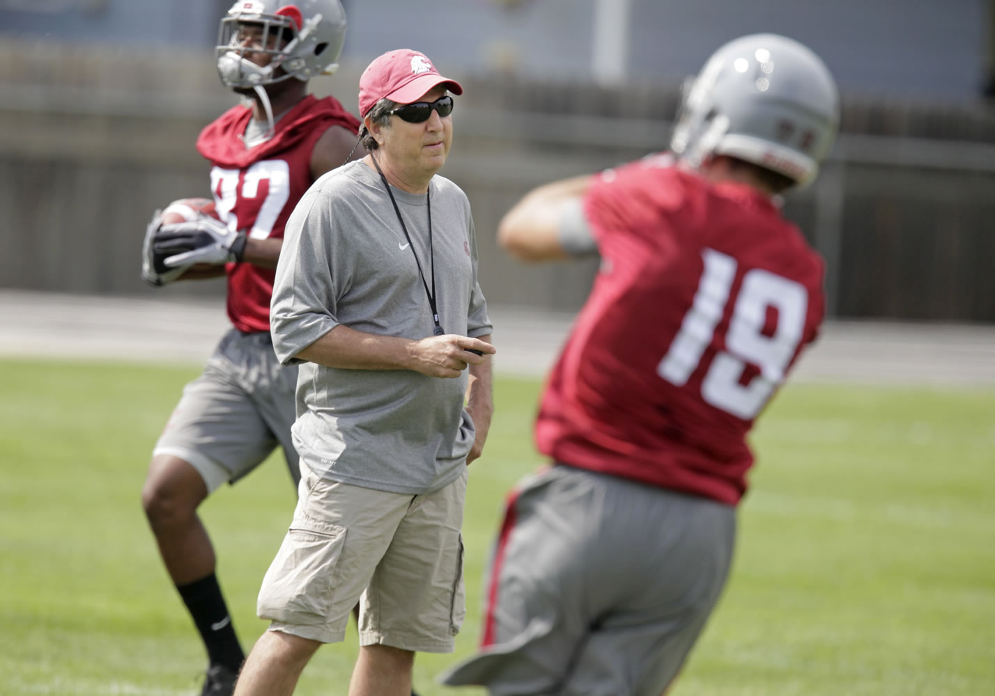 Washington State head coach Mike Leach, center, watches wide receivers Brett Bartolone, right, and Bobby Ratliff, left, run drills during the fall camp opening practice.