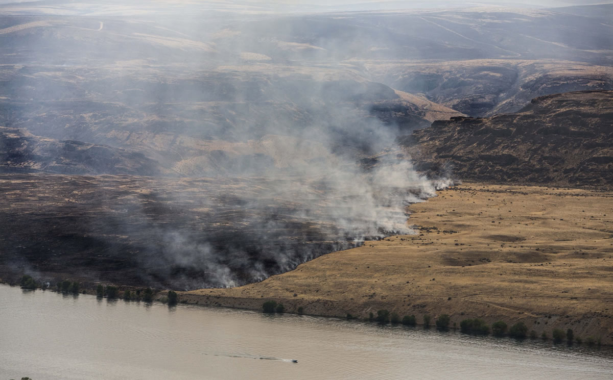 The Colockum Pass fire burns in the mountains Monaday and has also burned its way down to the banks of the Columbia River.