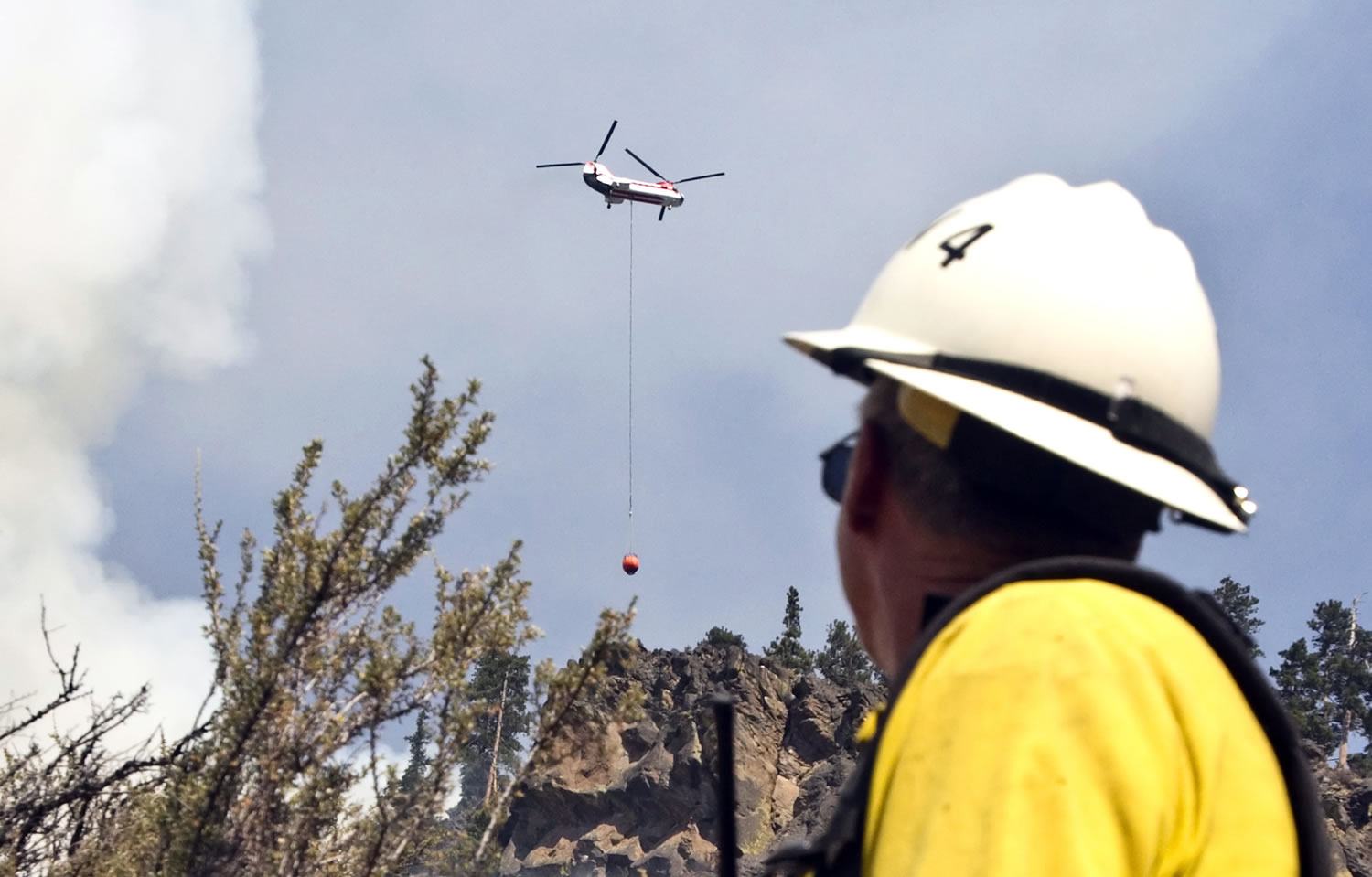 Firefighter Mike Ryan watches as a Chinook helicopter drops water on the Wild Rose fire along U.S.