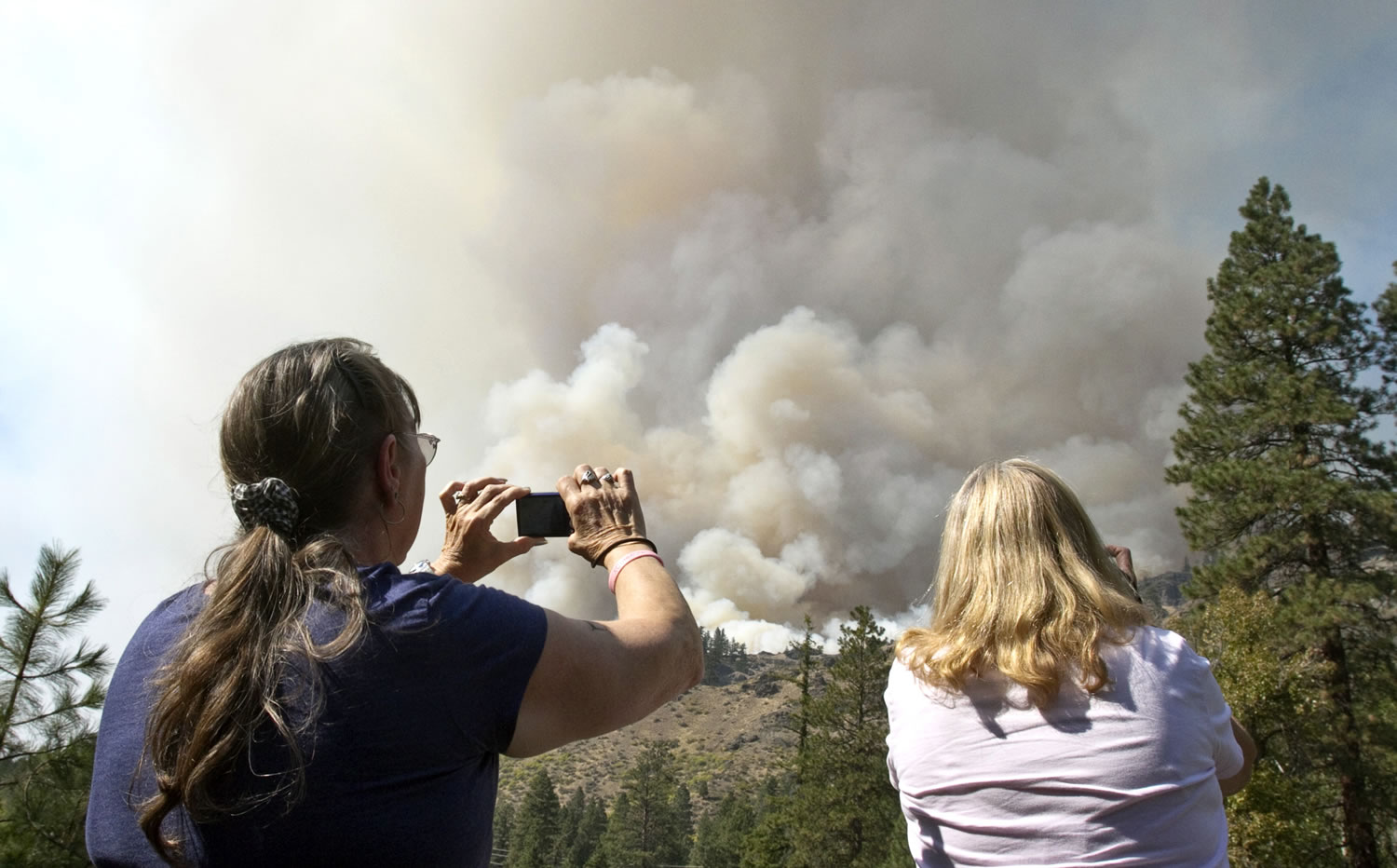 Vicky Olse, left, and Linda Bowers take photos of the Wild Rose Fire along U.S. Highway 12 west of Naches on Sunday.