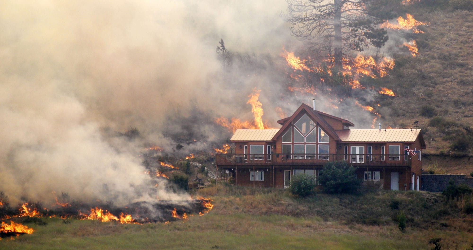 Flames surround a house Tuesday on a hillside above Bettas Road near Cle Elum.