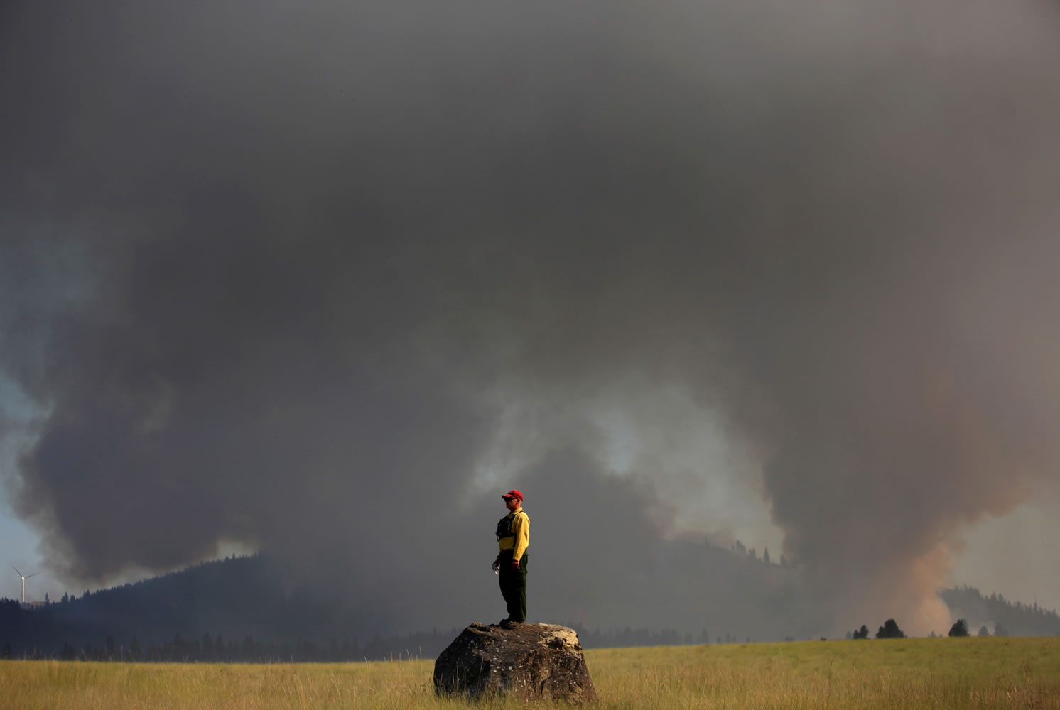 Marcus Johns with the Department of Natural Resources watches as the Taylor Bridge Fire burns on the south side of Highway 970 near Swauk Prairie Road on Wednesday near Cle Elum.
