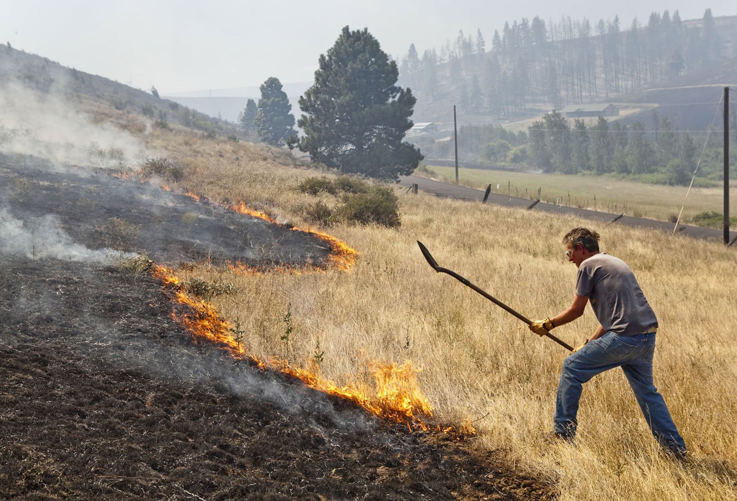 Homeowner David Firth tries to beat back a brush fire heading toward his home as a wildfire burns Tuesday in Cle Elum.