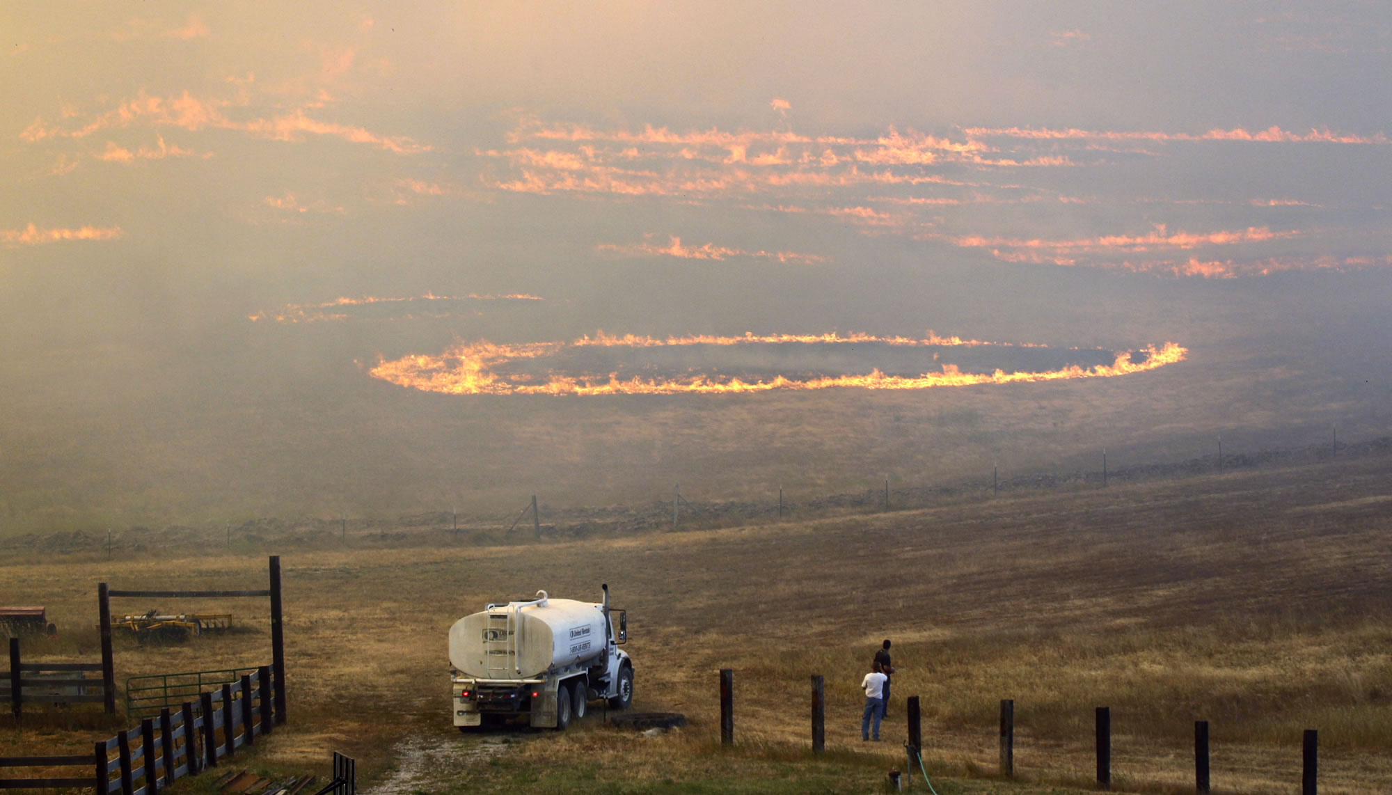 Men watch as fire roars across ranch land Tuesday on Bettas Road near Cle Elum.