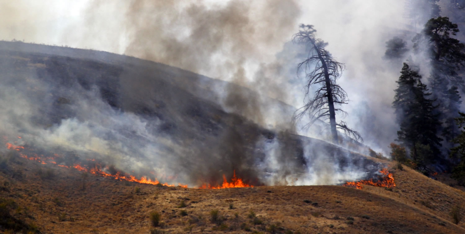 Flames burn at one end of a wildfire Monday near Wenatchee, Wash.