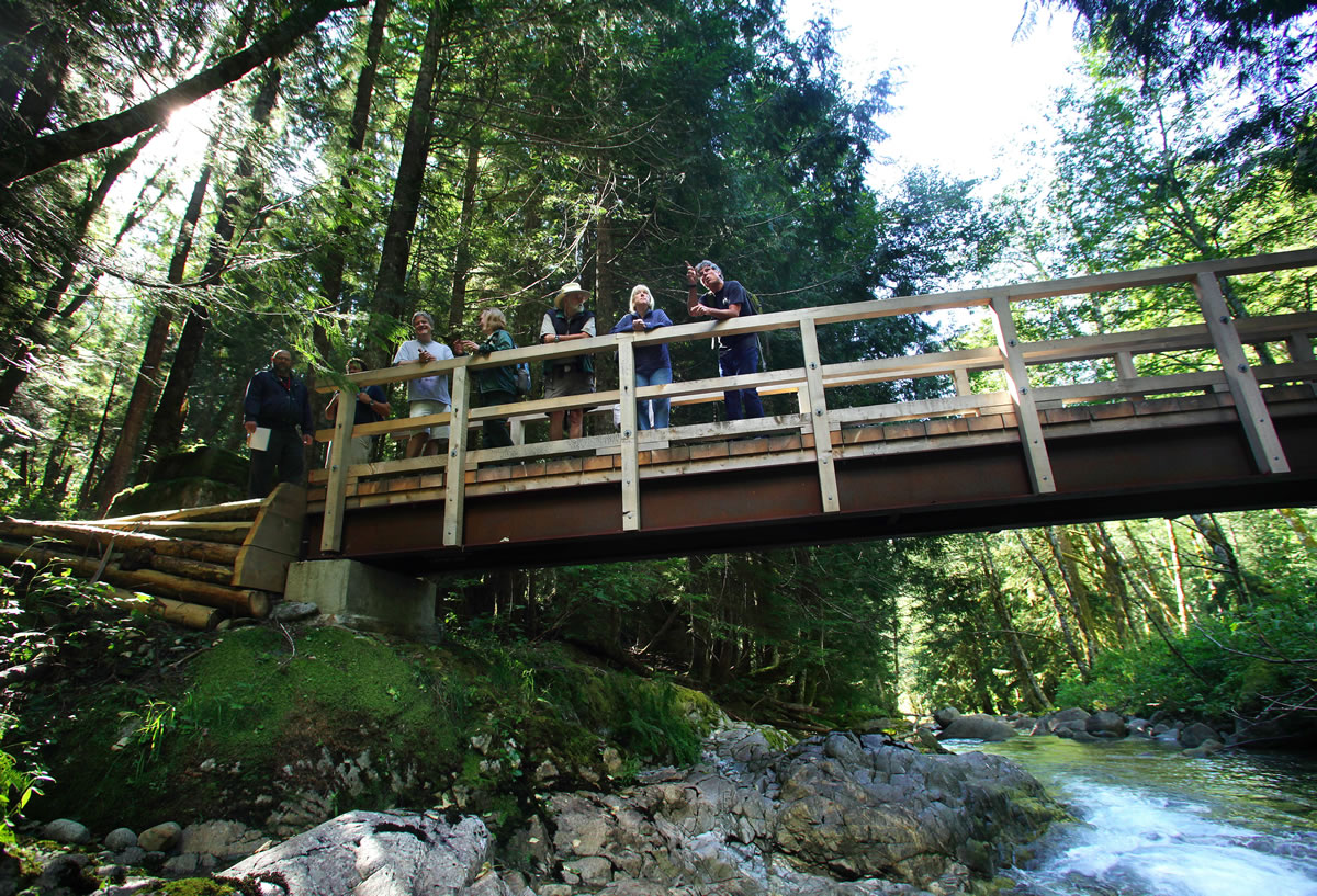 Mike Town, right, with Friends of the Wild Sky, points out a feature along the trail to Sen. Patty Murray, second from right, on the bridge over Martin Creek while hiking Tuesday toward the Wild Sky Wilderness in Index.