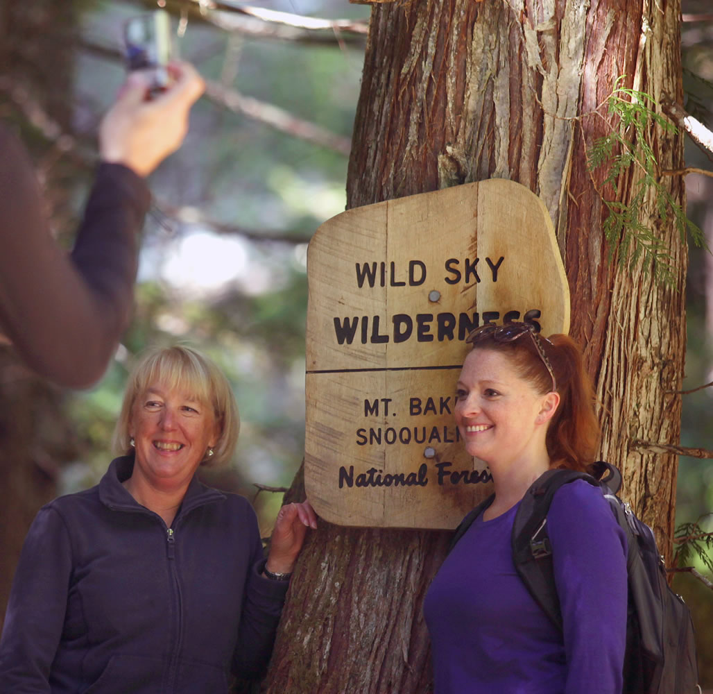Sen. Patty Murray, left, has her photo taken Tuesday in front of the sign entering the Wild Sky Wilderness during a hike in Index.