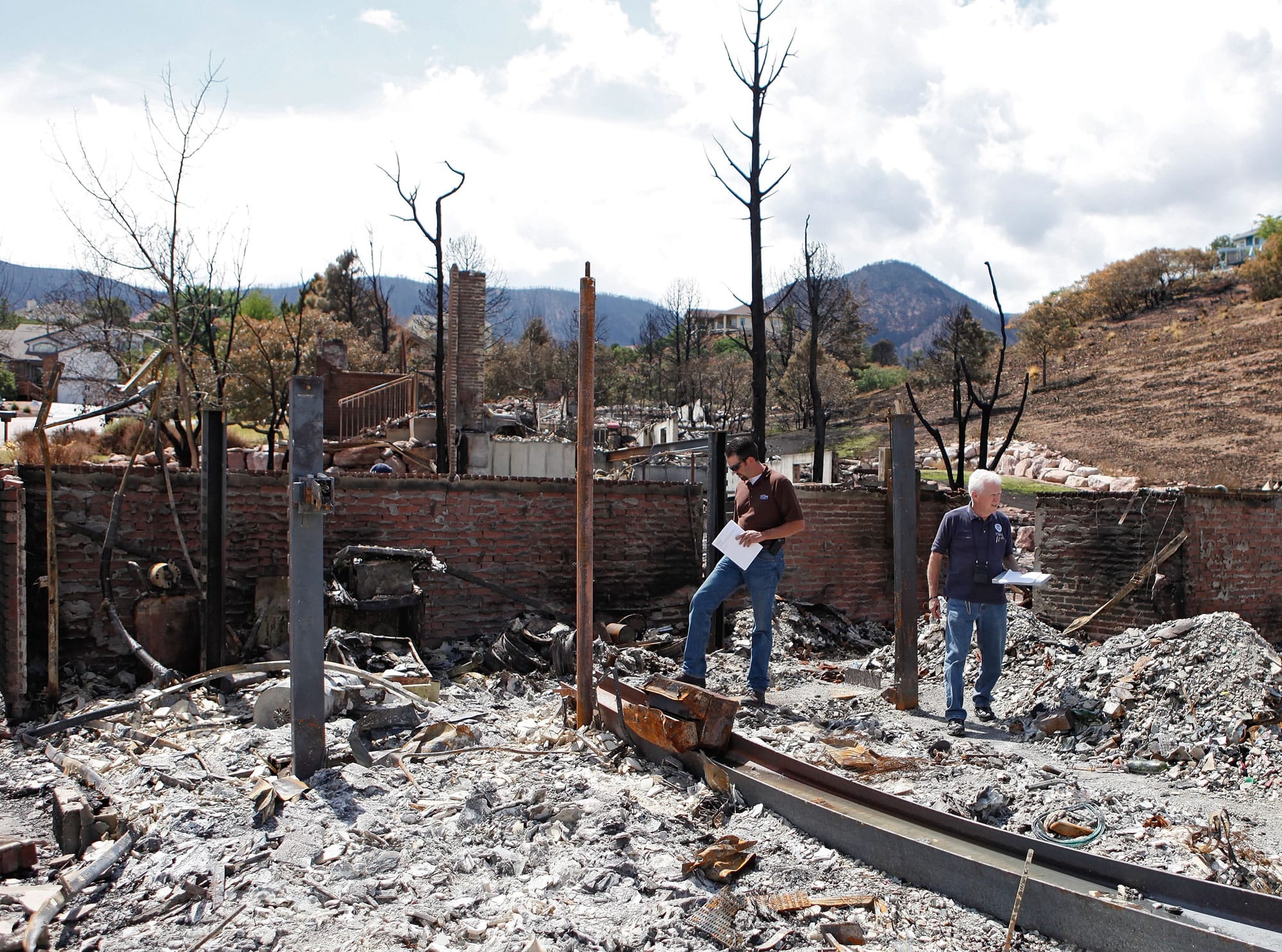 Members of FEMA walk through the ashes of a burned home in Colorado Springs, Colo.
