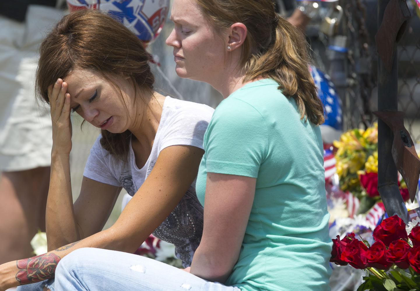 Juliann Ashcraft, left, the widow of Andrew Ashcraft, sits by a memorial for the fallen firefighters in front of Prescott Fire Station 7 on July 1.