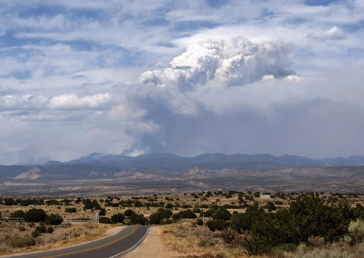 This photo released courtesy Zach Bryan shows a massive plume of smoke rises from the Thompson Ridge Fire burning in the Jemez Mountains north of Rio Rancho, N.M., on Tuesday, June 4, 2013. Fire officials said the blaze charred about 7 square miles by Tuesday and firefighters were facing hot, dry and windy conditions.
