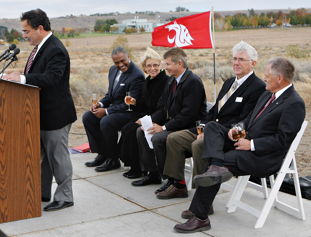 Dan Bernardo, left, vice president and dean of the Washington State University College of Agricultural, Human and Natural Resource Sciences, addresses a crowd at the dedication of WSU Tri-Cities Wine Science Center in Richland. Seated are Gov.