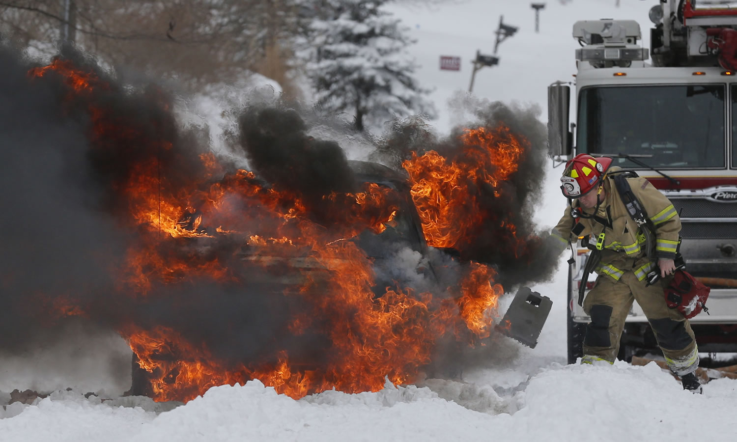 A Lawrence firefighter places wheel blocks as he prepares to extinguish a vehicle fire in Lawrence, Kan., on Thursday.
