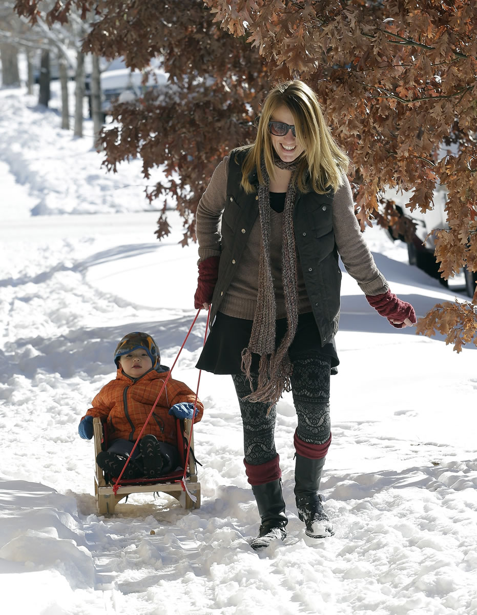 Babysitter Faith Whitney pulls two-year-old Teddy through the snow on a sled in Denver on Monday.