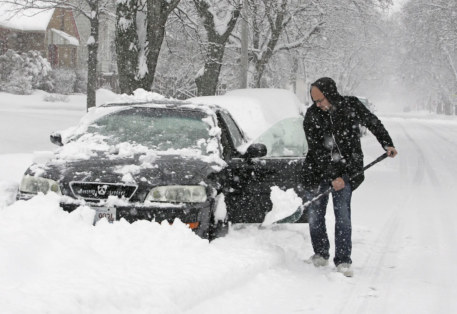 Cris Colon shovels snows from around his car Tuesday in Rockford, Ill.