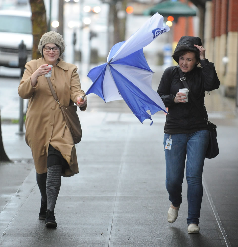 Anne Campbell, left, deals with a busted umbrella while walking in high winds on her way back to work from getting coffee with coworker Jani Snell in Bellingham on Monday.
