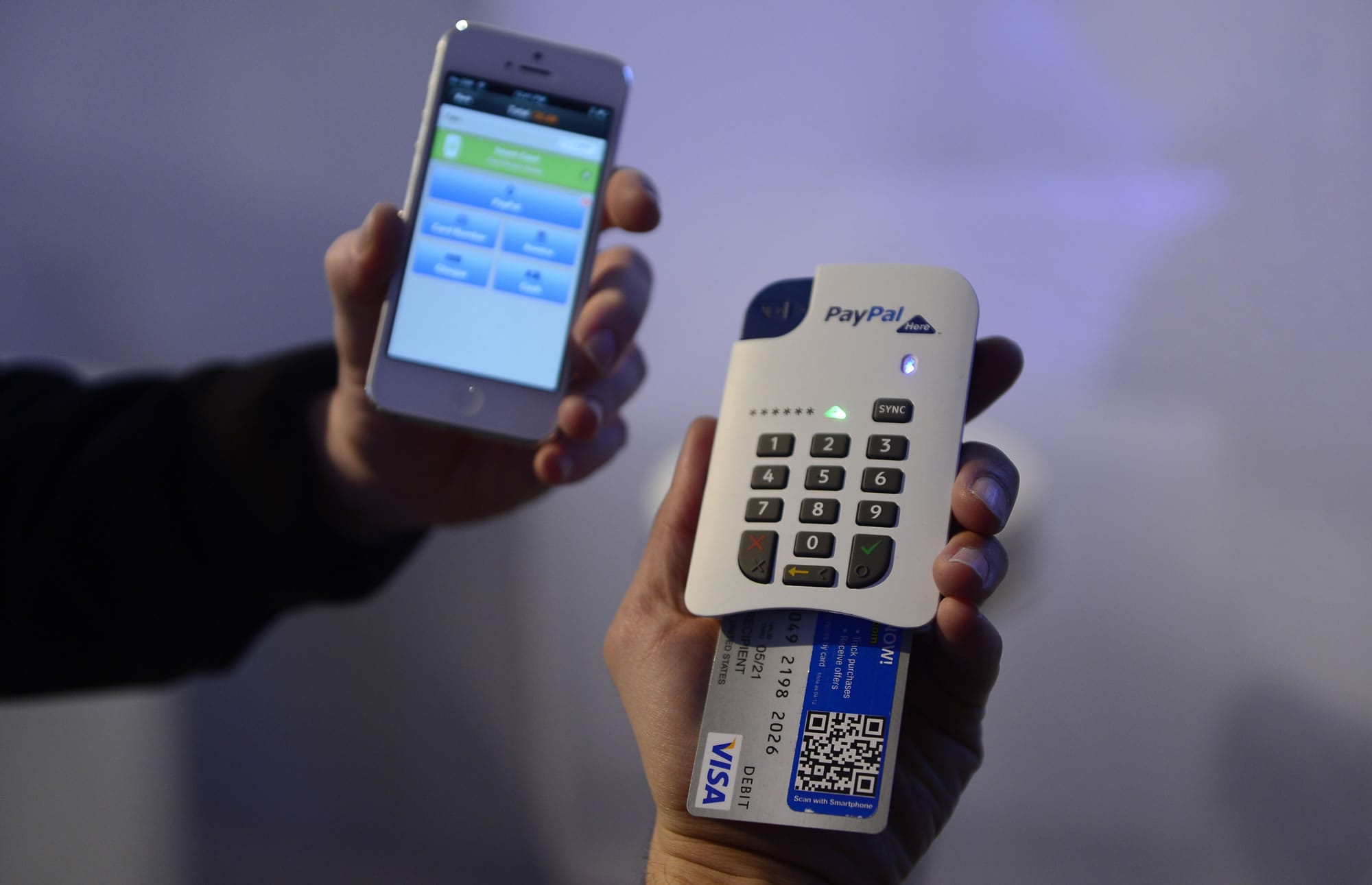 A man uses the &quot;Paypal here&quot; system of payment with a phone Wednesday at the Mobile World Congress in Barcelona, Spain.