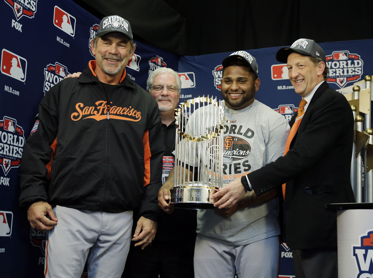 San Francisco Giants owner Bill Neukom, right to left, Pablo Sandoval, Brian Sabean and Bruce Bochy hold the Commissioner's Trophy after winning the World Series.